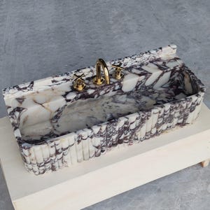 Contemporary Calacatta Viola marble sink with creamy white tones and striking purple veining, ideal for modern interiors.