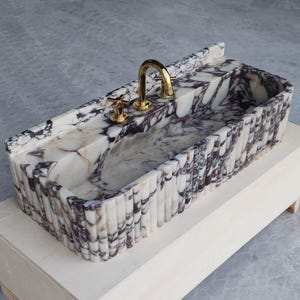 Handcrafted sink in Calacatta Viola marble, combining artisanal quality with stunning natural beauty for high-end bathrooms.
