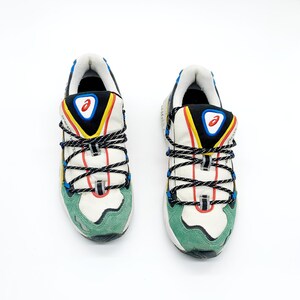 May include: A pair of white sneakers with green, blue, yellow, and black accents. The sneakers have a lace-up closure and a chunky sole.