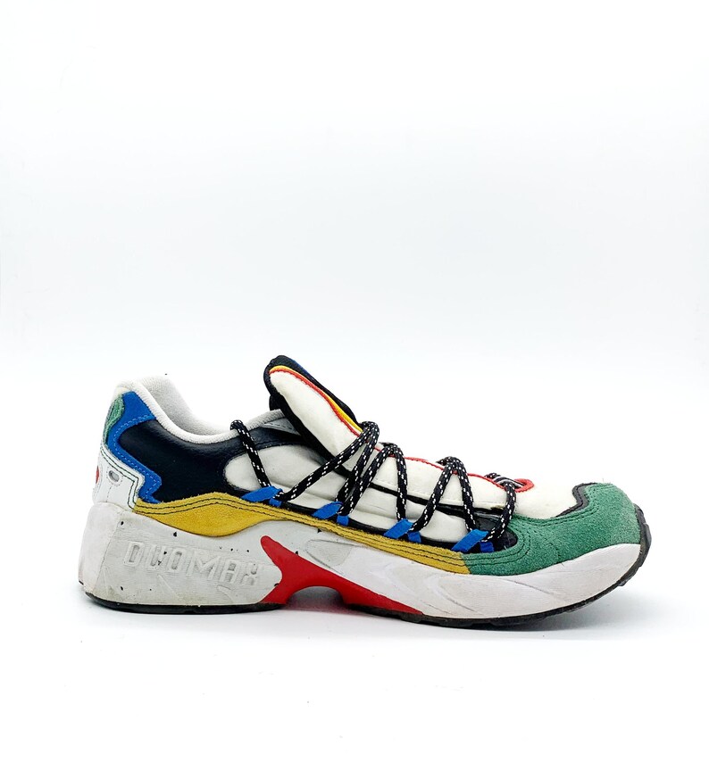 May include: White, black, yellow, blue, and green multi-colored sneakers with black laces. The brand name "DRUMOHR" is printed on the side of the shoe.