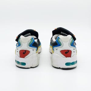 May include: A pair of white, blue, black, and red sneakers with a velcro strap. The sneakers have a multi-colored design and a white sole.
