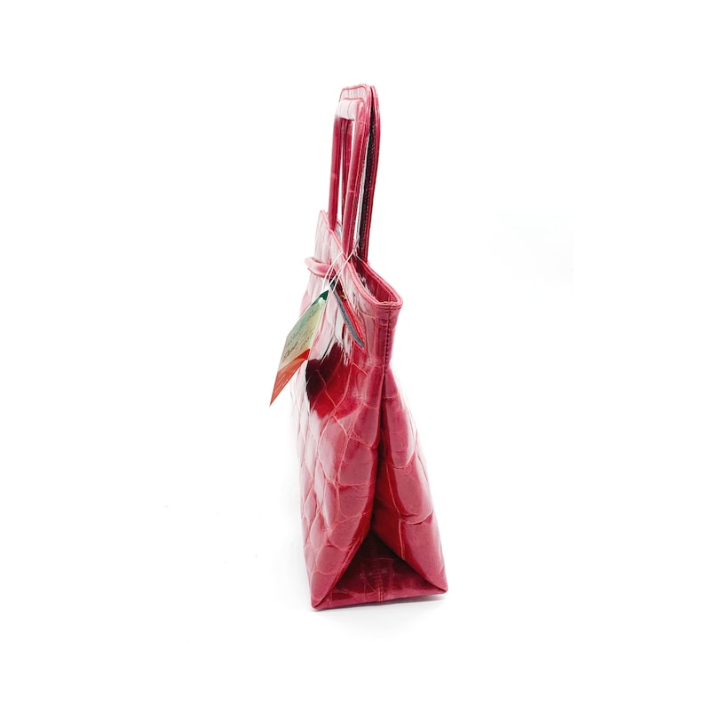 May include: A red leather handbag with a crocodile-embossed pattern. The bag has two top handles and a flap closure.