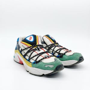 May include: A pair of white, green, yellow, blue, and black sneakers with black laces. The sneakers have a chunky sole and a logo on the side.
