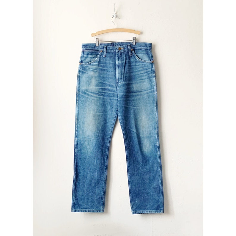 May include: A pair of light blue denim jeans with a straight leg fit. The jeans have a classic five-pocket design and a button fly.