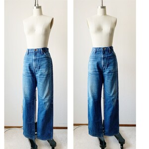 May include: A pair of blue denim jeans with a high waist and wide legs. The jeans are on a white mannequin.