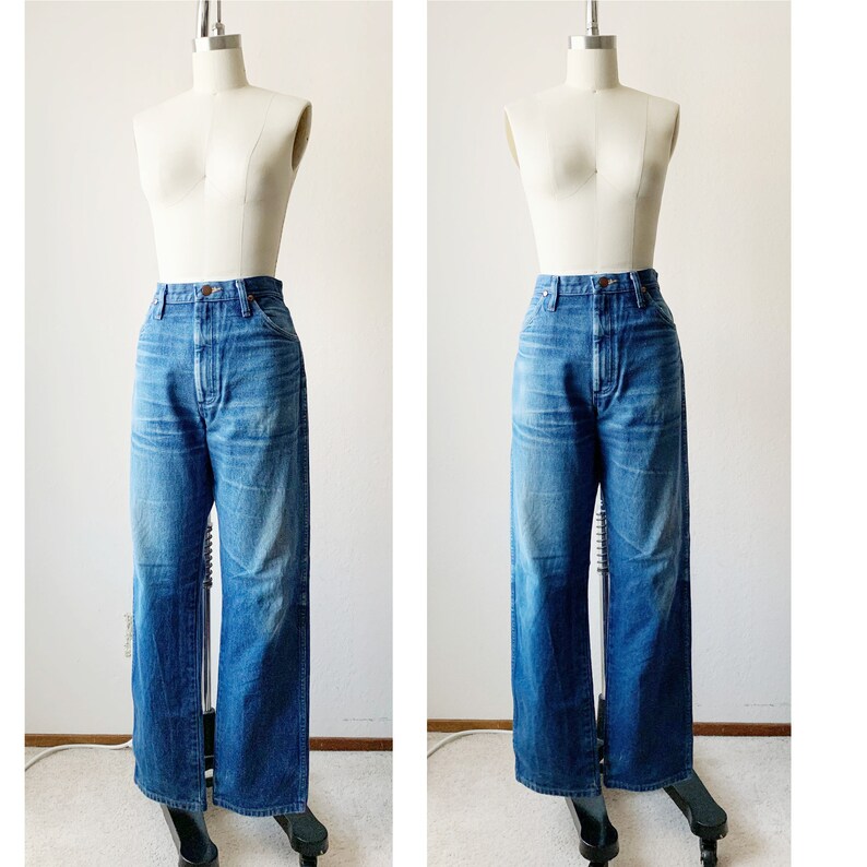 May include: A pair of blue denim jeans with a high waist and wide legs. The jeans are on a white mannequin.