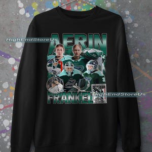 Puede incluir: Sudadera negra con un dise&ntilde;o que presenta el nombre "AERIN FRANKEL" en verde y blanco. El dise&ntilde;o incluye m&uacute;ltiples im&aacute;genes de una jugadora de hockey con uniforme verde y blanco, con el texto "HighEndStoreUs".