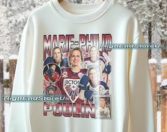 Pode incluir: Camisola creme com uma colagem de imagens de Marie-Philip Poulin, jogadora de hóquei. A camisola tem o nome "MARIE-PHILIP POULIN" impresso em vermelho e branco. O texto "HighEndStoreUs" também é visível.