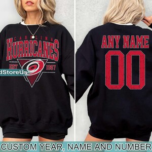 May include: Black sweatshirt with a Carolina Hurricanes logo and the text "Carolina Hurricanes Est 1997". The back of the sweatshirt has the text "Any Name 00".