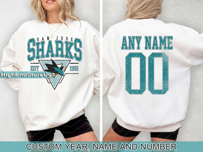 May include: White sweatshirt with a teal blue San Jose Sharks logo and the text "San Jose Sharks Est 1991". The back of the sweatshirt has the text "Any Name 00" in teal blue.