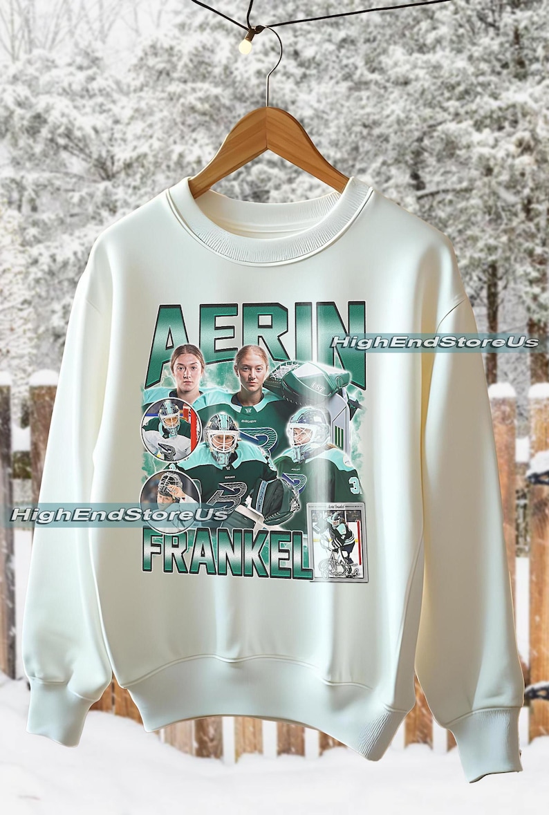 Puede incluir: Sudadera color crema con un dise&ntilde;o gr&aacute;fico verde y blanco con el nombre "AERIN FRANKEL". El dise&ntilde;o incluye im&aacute;genes de jugadores de hockey con uniformes verdes y blancos. El texto "HighEndStoreUs" tambi&eacute;n es visible.