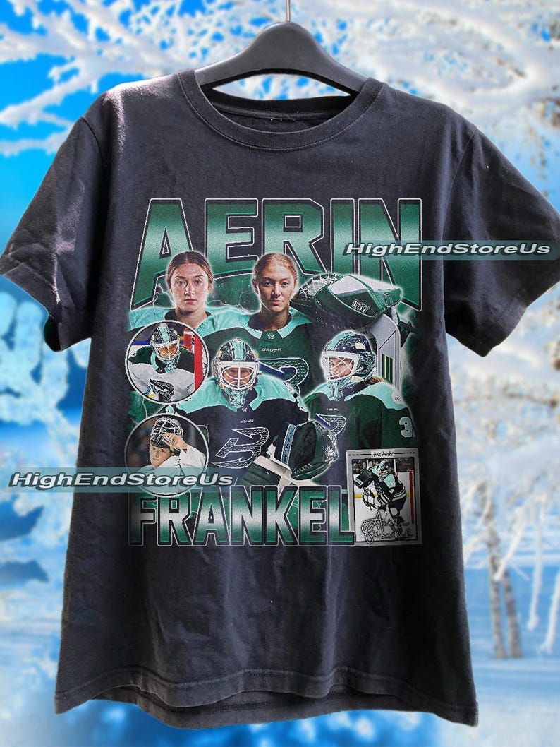 Puede incluir: Camiseta negra con un dise&ntilde;o tem&aacute;tico de hockey. Presenta im&aacute;genes de una jugadora de hockey y el nombre "AERIN FRANKEL" en verde y blanco. Tambi&eacute;n se ve el texto "HighEndStoreUs". El dise&ntilde;o incluye una tarjeta de hockey.
