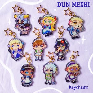 Può includere: Una collezione di portachiavi con personaggi in stile anime. Ogni portachiavi presenta un design unico del personaggio con colori e dettagli vibranti, attaccato a una catena dorata e un ciondolo a forma di stella. La parola "Keychains" è in basso.