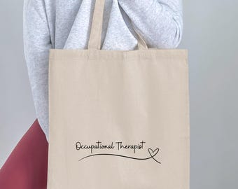 May include: A beige tote bag with black text that reads "Occupational Therapist" with a small heart symbol.