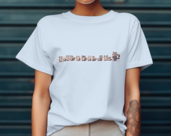 May include: A light blue t-shirt featuring a line of cartoon raccoons printed on the front. The raccoons are all different colours and have different expressions.