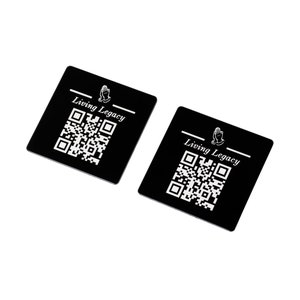 May include: Two black square coasters with white text and a QR code. The text reads "Living Legacy" with a praying hands graphic above the text. The QR code is in the center of the coaster.