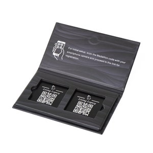 May include: Open black box with two rectangular cards featuring QR codes and the text "Living Legacy." The box's interior has a wood-grain pattern. Text on the inside cover instructs users to scan the Medallion code for registration.
