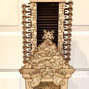 May include: Wooden Christmas advent calendar with a fireplace, Christmas tree, and Santa Claus. The calendar has 24 numbered key-shaped ornaments. The fireplace has stockings and gifts. The design is laser cut.