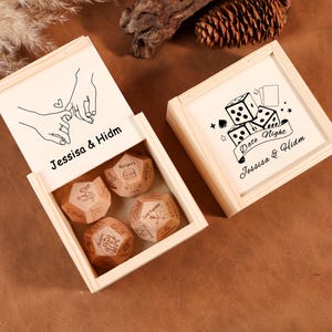 Può includere: Set di scatole di legno con quattro dadi poliedrici e un coperchio con un disegno a tratto di mani intrecciate e la scritta "Jessica & Hidm". Il secondo coperchio ha dadi e le parole "Date Night".