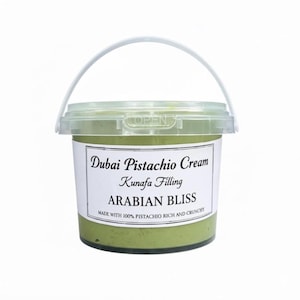 May include: A clear plastic container of Dubai Pistachio Cream, a Kunafa filling. The label reads "ARABIAN BLISS" and "MADE WITH 100% PISTACHIO RICH AND CRUNCHY". The cream is a light green color, and the container has a white handle.