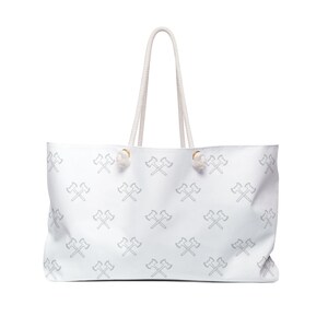 May include: White canvas tote bag with a repeating pattern of crossed axes in a light gray color. The bag has white rope handles.