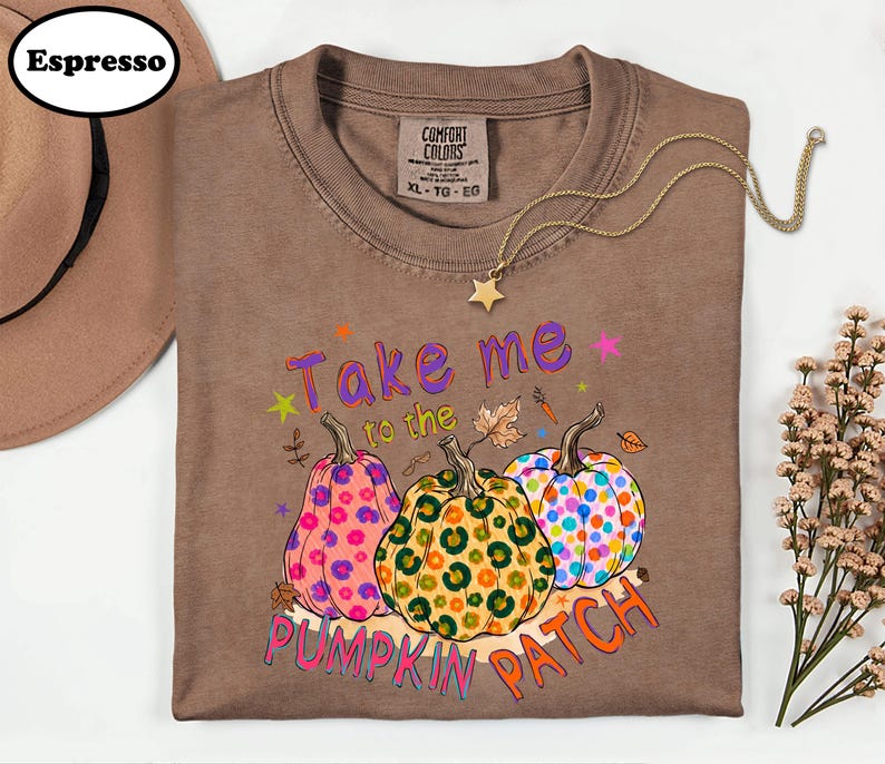 a brown t-shirt with a colorful pumpkin patch design, along with a hat and some flowers.