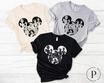 May include: Three t-shirts with a black and white silhouette of Mickey Mouse's head with Disney Princesses inside. The t-shirts are in beige, gray, and black.