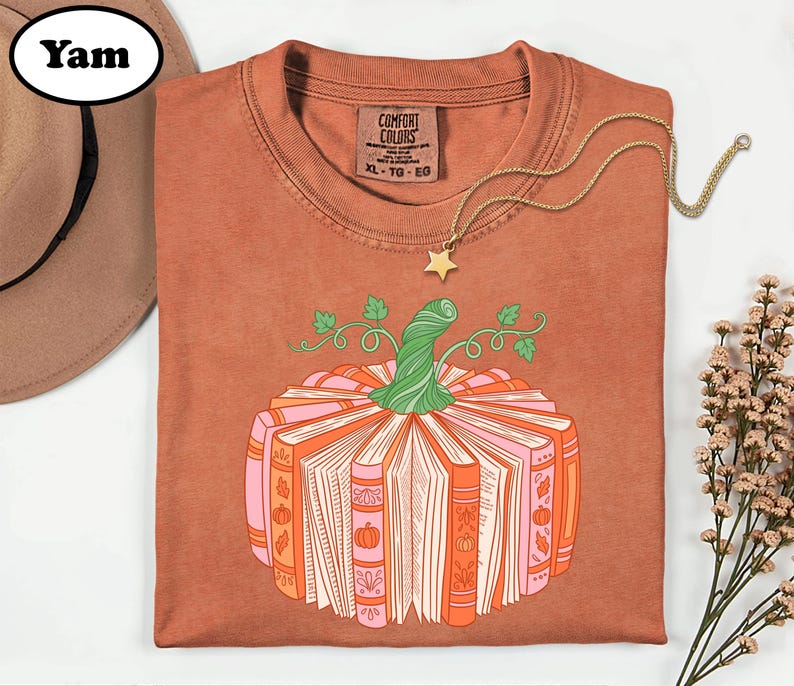 a brown t-shirt with a pumpkin graphic and a necklace, along with a hat and some flowers, all arranged on a white background.
