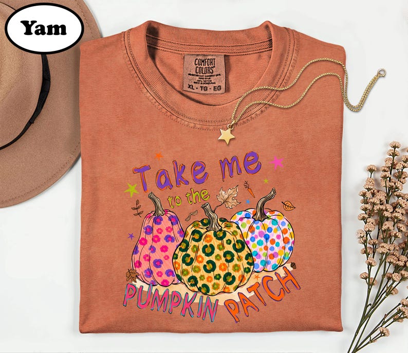 a brown t-shirt with a colorful pumpkin patch design, along with a hat and some flowers.