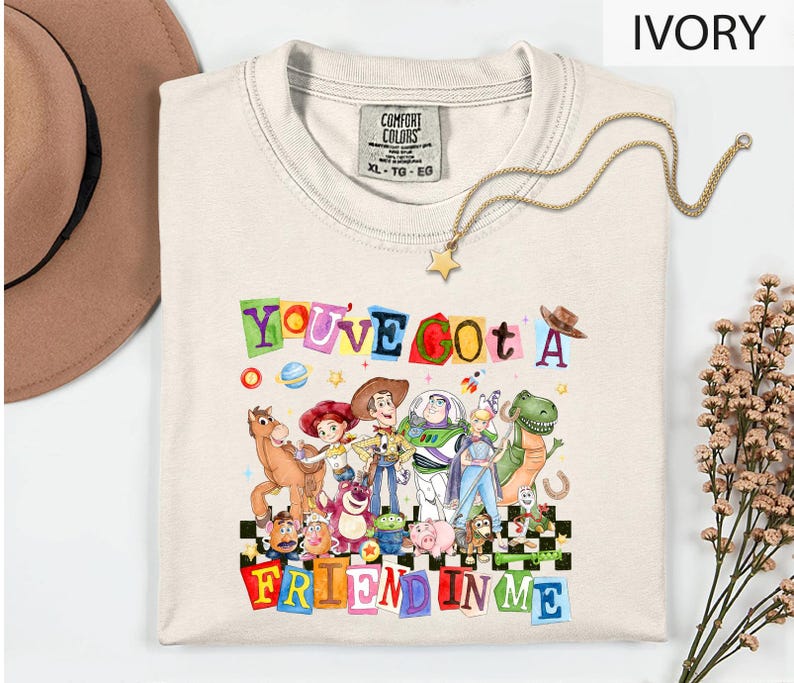 A white t-shirt with a colorful graphic design featuring characters from the Toy Story movie, along with the text "You've Got a Friend in Me".