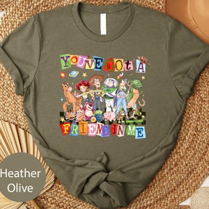 A t-shirt with a colorful graphic design featuring characters from the Toy Story franchise, including Woody, Buzz Lightyear, and other beloved characters.