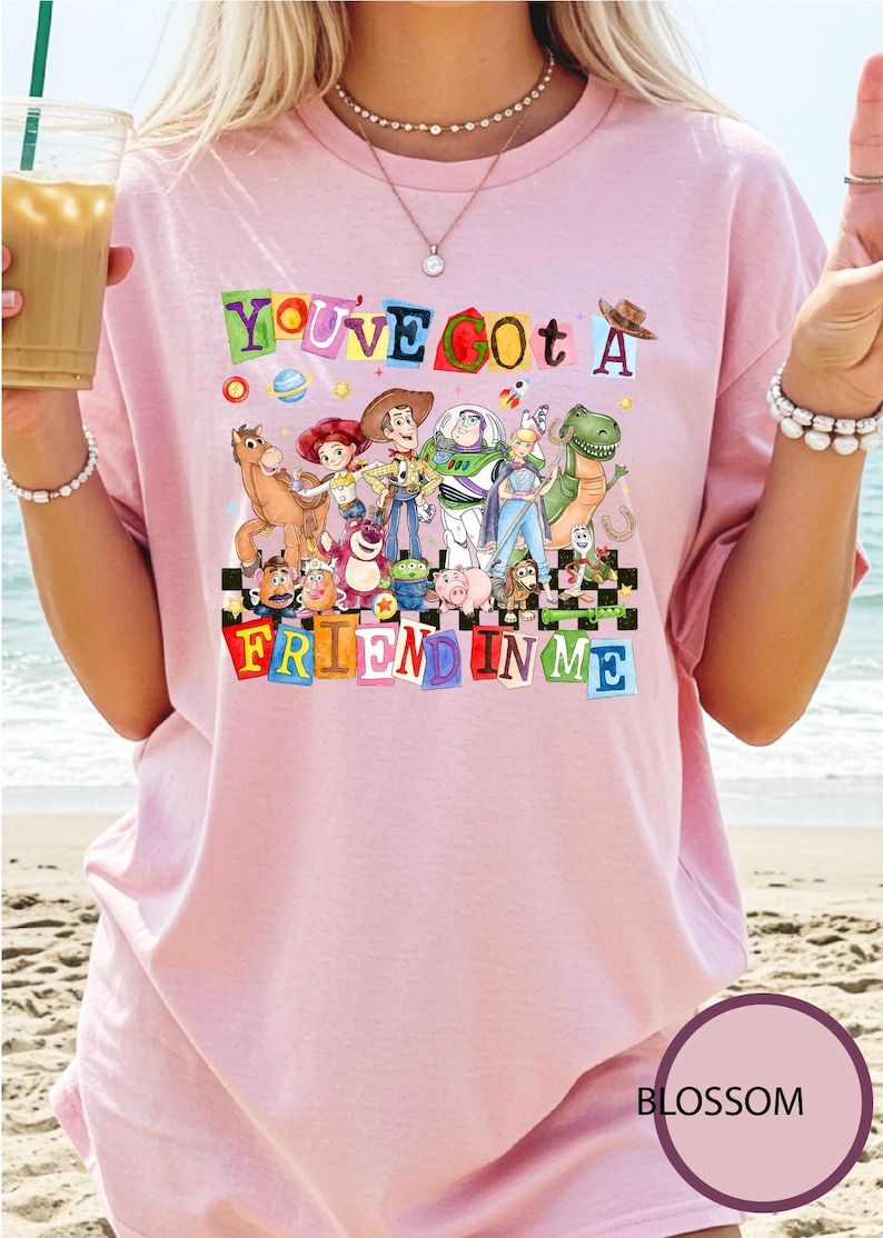 A woman wearing a pink t-shirt with a colorful graphic of characters from Toy Story, including Woody, Buzz Lightyear, and other beloved characters, along with the text "You've got a friend in me".