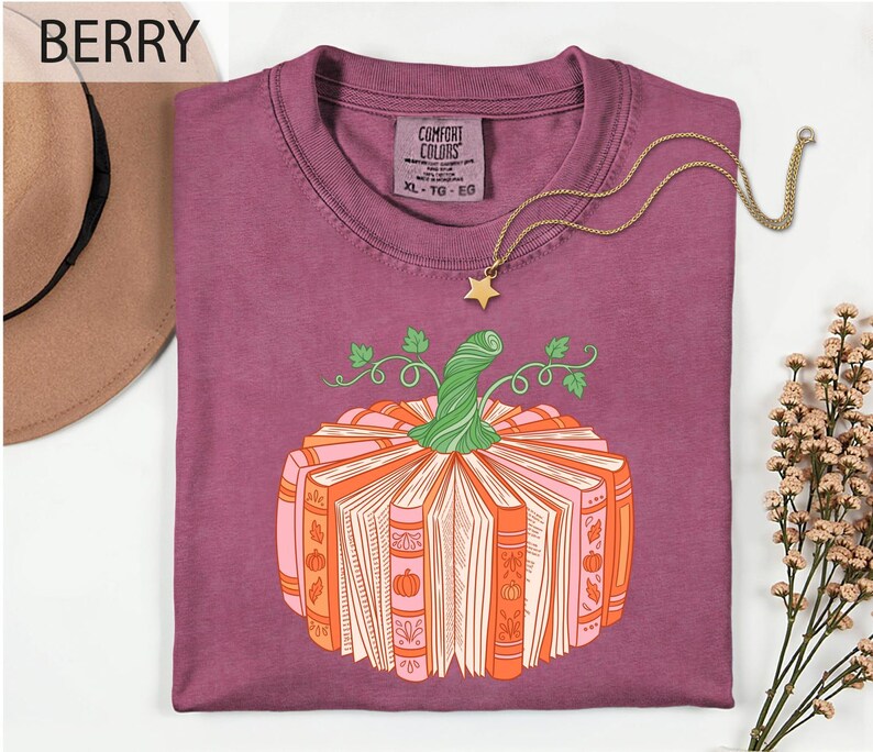 a purple t-shirt with a pumpkin graphic and a necklace, along with a hat and some flowers.