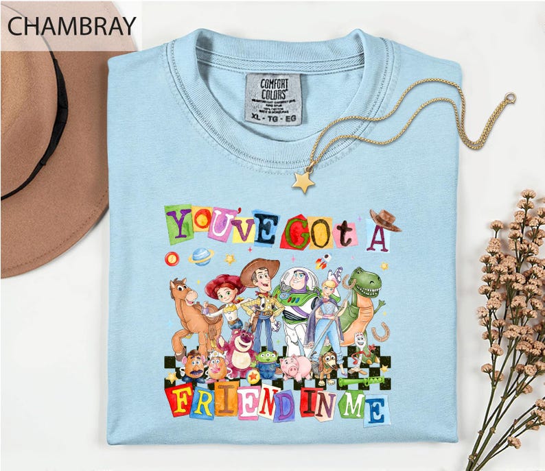 a light blue t-shirt with a colorful graphic design of characters from the Toy Story movie, along with the text "You've Got a Friend in Me".