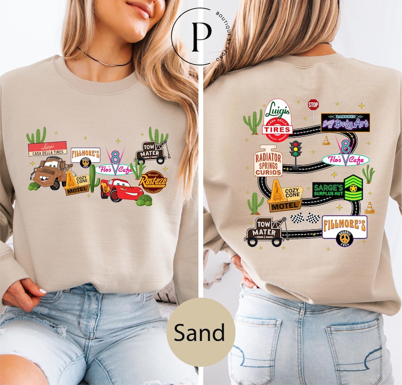 a woman wearing a beige sweater with various car-related logos and illustrations on the front and back.
