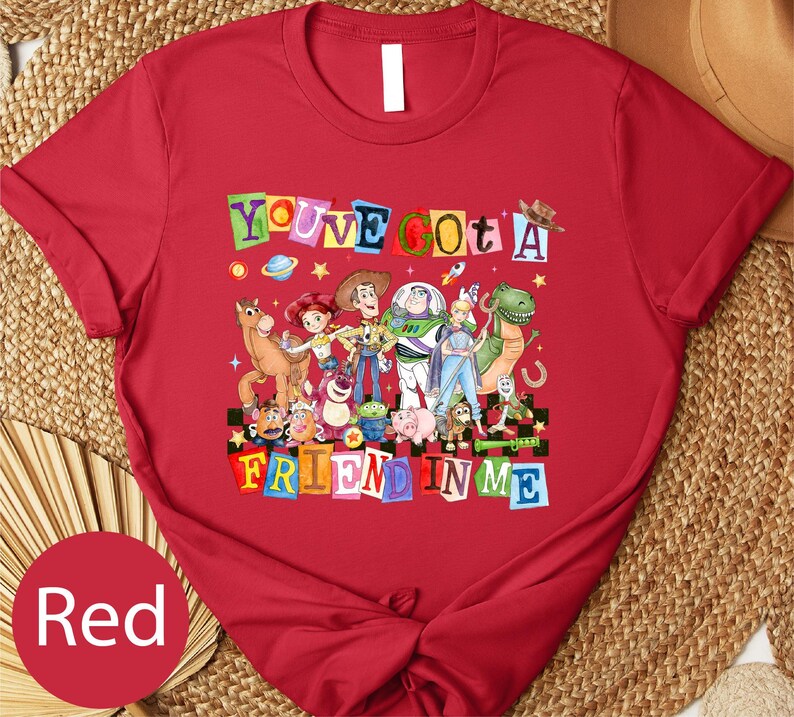 A red t-shirt with a colorful graphic design featuring characters from the Toy Story franchise, including Woody, Buzz Lightyear, and other beloved characters.