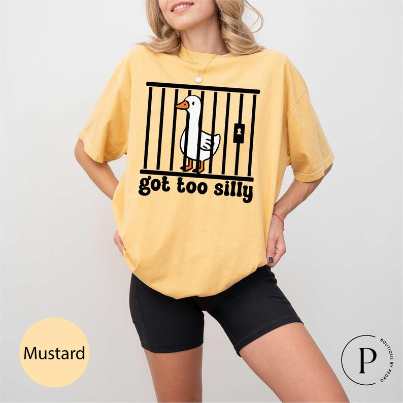 Peut inclure: T-shirt moutarde avec un dessin d'oie derri&egrave;re des barreaux et le texte "got too silly". Le t-shirt est de coupe ample, et la couleur est &eacute;tiquet&eacute;e "Mustard".