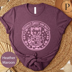 A purple t-shirt with a graphic design featuring a cat and the text "Usually Sweet and Nice BUT FICK ICE" printed on it.
