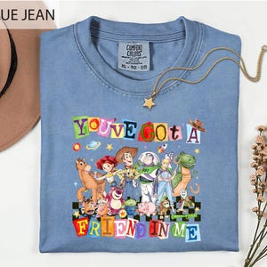 A blue t-shirt with a colorful graphic of characters from the Toy Story movie, along with the text "You've Got a Friend in Me" printed on it.