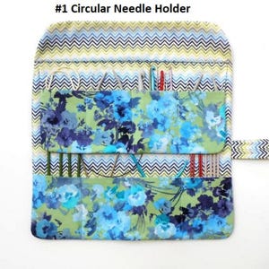 May include: A fabric circular needle holder with a floral and chevron pattern. The holder is open, revealing various knitting needles and crochet hooks. The text "#1 Circular Needle Holder" is at the top.