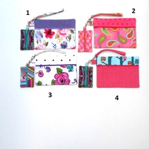 May include: Four colorful wristlet wallets with matching small zippered pouches. Designs include floral, paisley, polka dot, and owl patterns. Each wallet has a wrist strap and a zipper closure. The wallets are in shades of pink, purple, and blue.