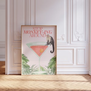 May include: A pink poster with the text "STOP MONKEY-ING AROUND" in red letters. A cartoon monkey is sitting on the rim of a martini glass filled with a pink liquid. Tropical leaves are in the background.