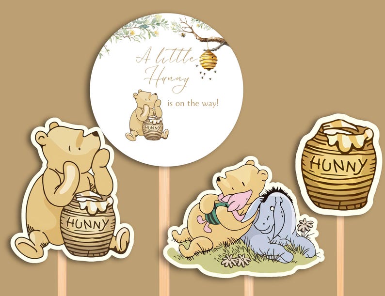 May include: Three Winnie the Pooh themed cake toppers. One round topper with a beehive and the text "A little Hunny is on the way!" Another topper features Winnie the Pooh holding a honey pot. The third topper shows Winnie the Pooh and Piglet sitting together.