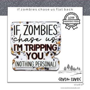May include: A clear, rectangular flat back with the text "IF ZOMBIES chase us I'M TRIPPING YOU. (NOTHING PERSONAL)". The design includes gold and brown glitter accents and a small illustration of trees. The words "seven coves studio" are also visible.