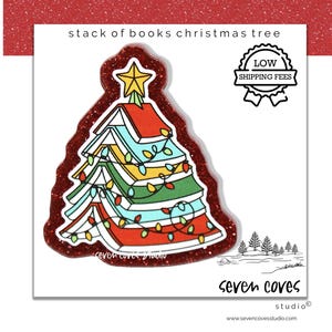 May include: A Christmas tree illustration made of stacked books, adorned with colorful lights and a star topper. The image has a red glitter border and includes the text "stack of books christmas tree". The design is from seven coves studio.