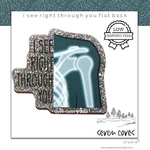 May include: A flat back pin with a glittery silver border. The pin features an X-ray image of a shoulder and the text "I SEE RIGHT THROUGH YOU". A "LOW SHIPPING FEES" badge is also present.