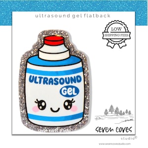 May include: A flatback charm in the shape of an ultrasound gel bottle. The bottle is white with blue stripes and the words "ULTRASOUND GEL". It has a red cap and a smiling face. The charm is outlined with glitter.