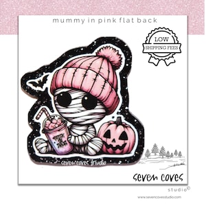 May include: A cartoon illustration of a mummy wearing a pink beanie and wrapped in bandages, holding a "Trick or Treat" drink, with a pink pumpkin. The image has a black glitter border and the text "mummy in pink flat back".
