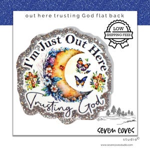 May include: A round, glitter-edged sticker with the text "I'm Just Out Here Trusting God." The design features a crescent moon, butterflies, flowers, and crosses. The sticker also has the text "out here trusting God flat back."