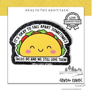 May include: A cute taco sticker with the text "It's okay to fall apart sometimes. Tacos do and we still love them." The taco is yellow with green lettuce, red tomatoes, and a smiling face. The sticker has a black glitter border.